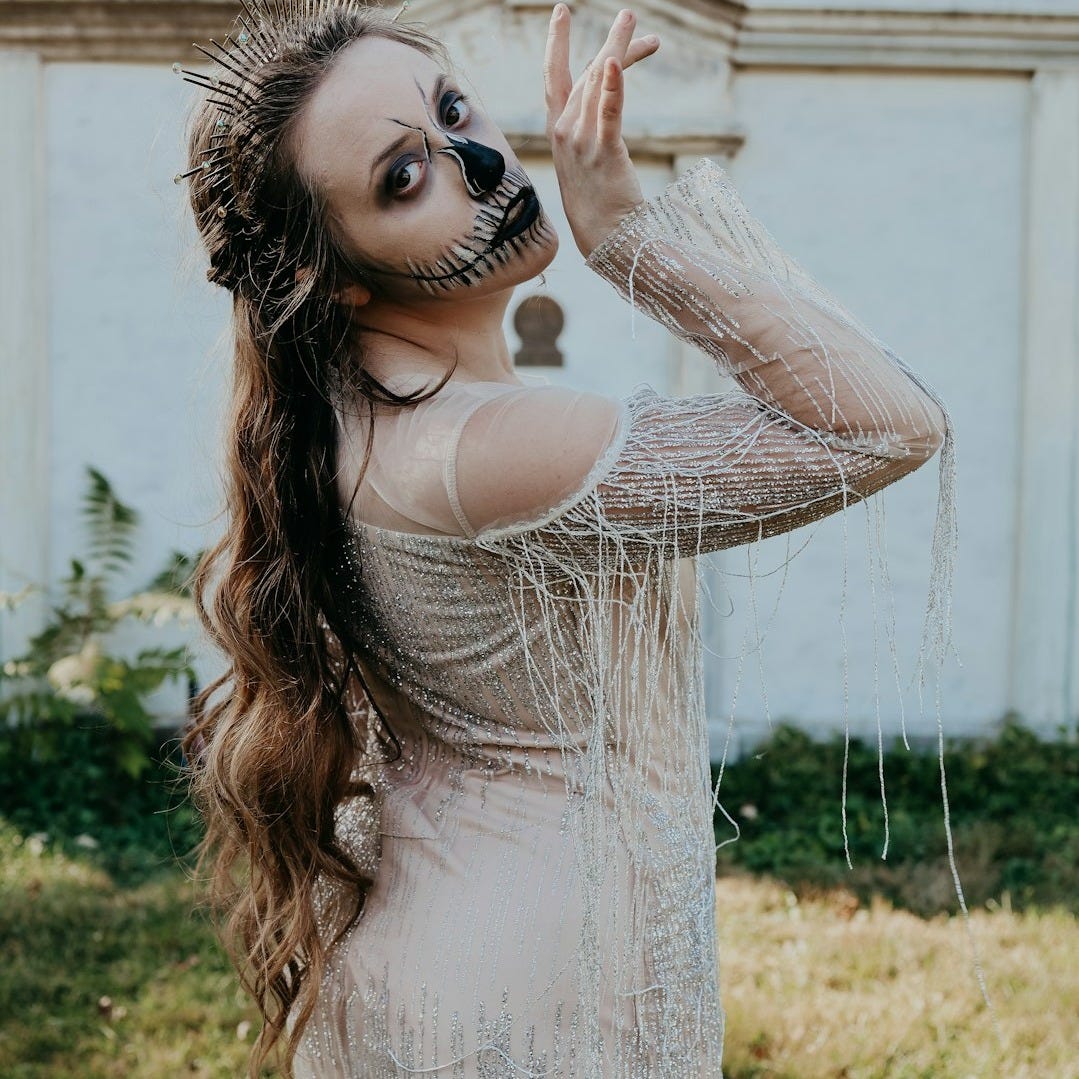 a woman in a white dress with makeup on her face