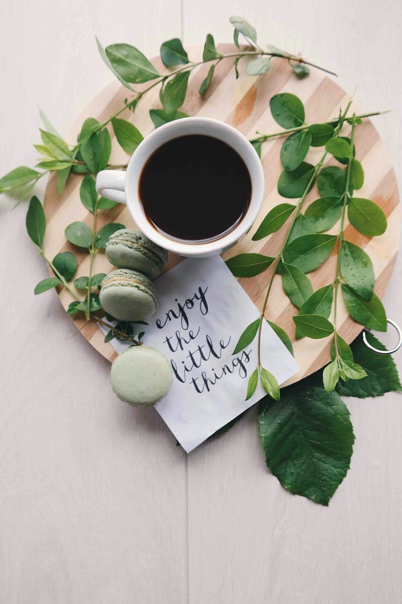 A cup of coffee with a note, “Enjoy the little things”. A cup of coffee with a note, “Enjoy the little things”.