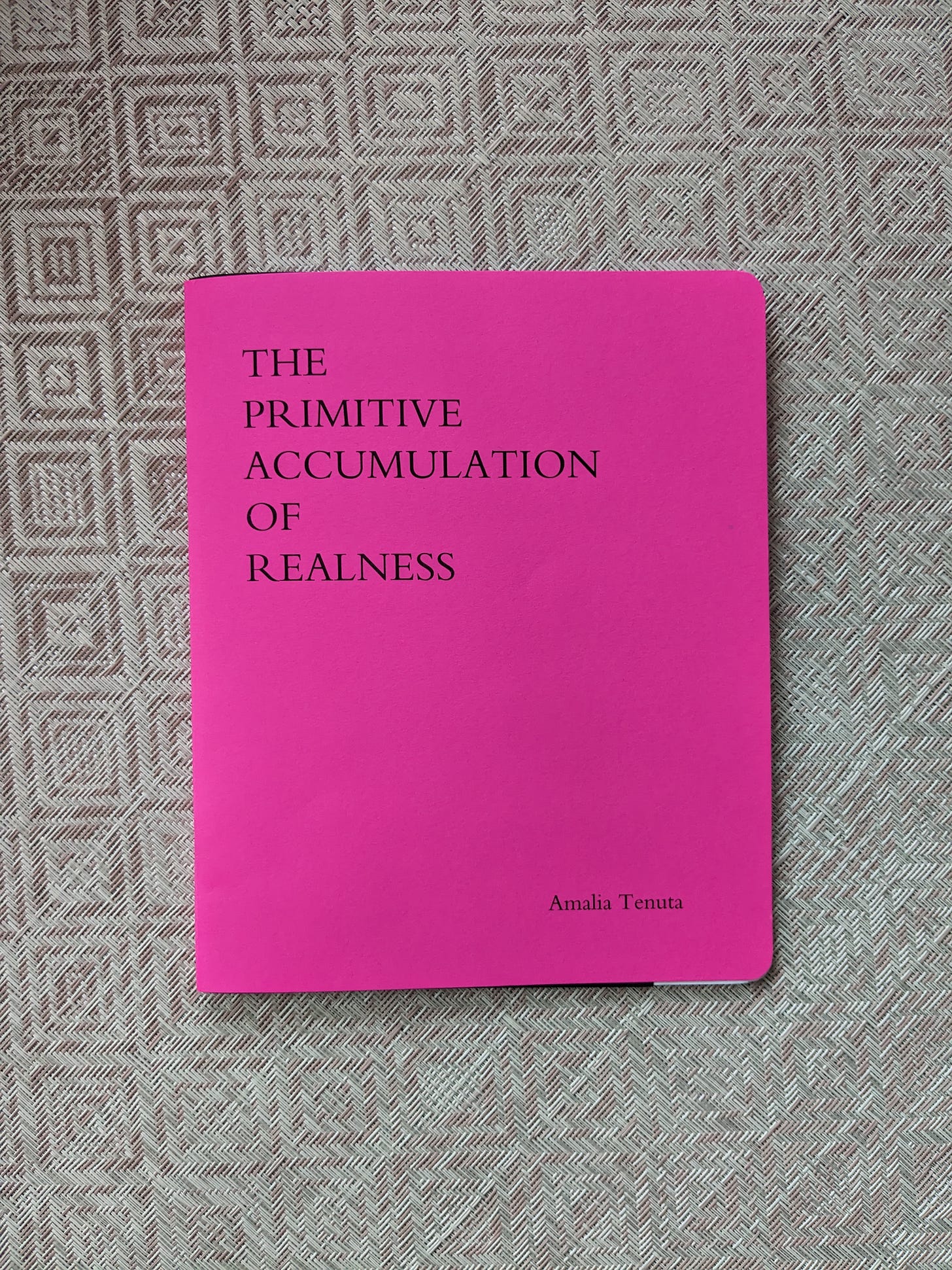 Photo of neon pink book on a pale pink mat.