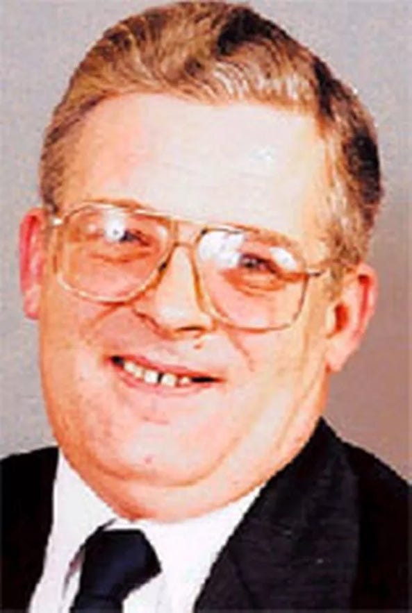 A person wearing glasses and a suit

Description automatically generated