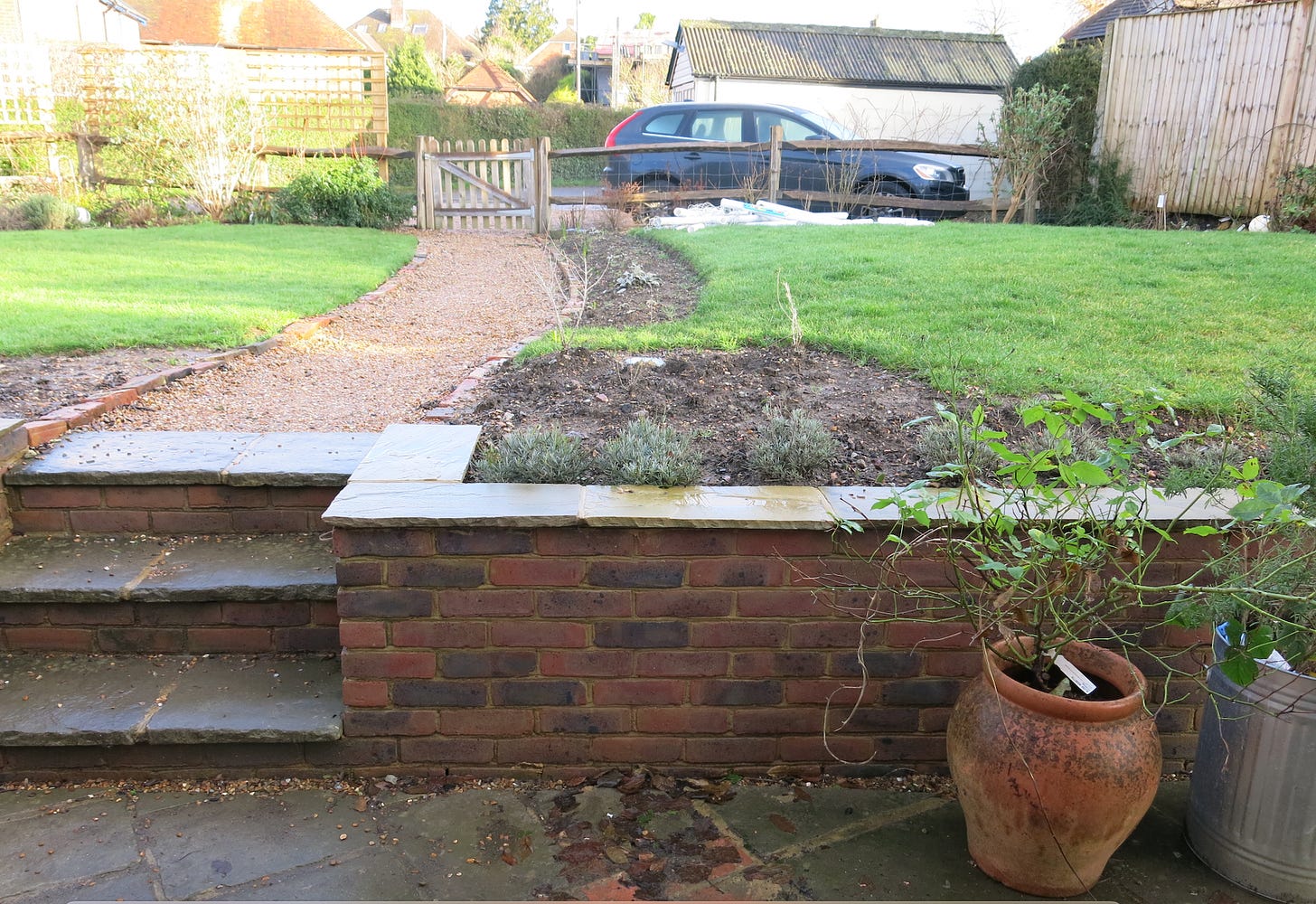 an empty garden with a brick wall and a car and garage