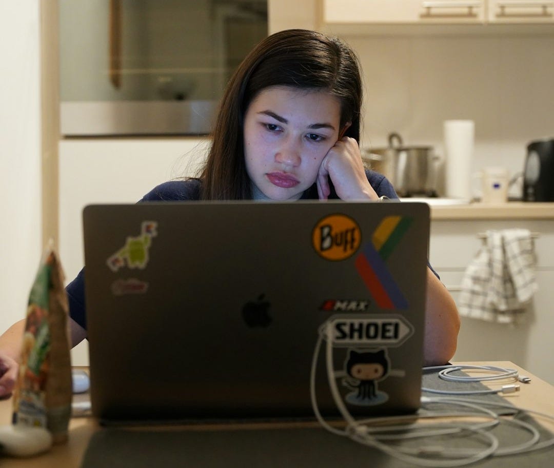 a woman sitting in front of a laptop computer a woman sitting in front of a laptop computer