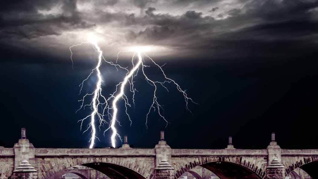 From a mass of ominous clouds, two blinding bolts of lightning strike an ornate stone bridge.