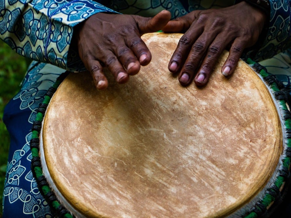 person tapping on traditional drum instrument