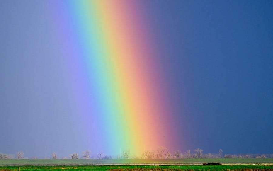 A bright rainbow above farm fields