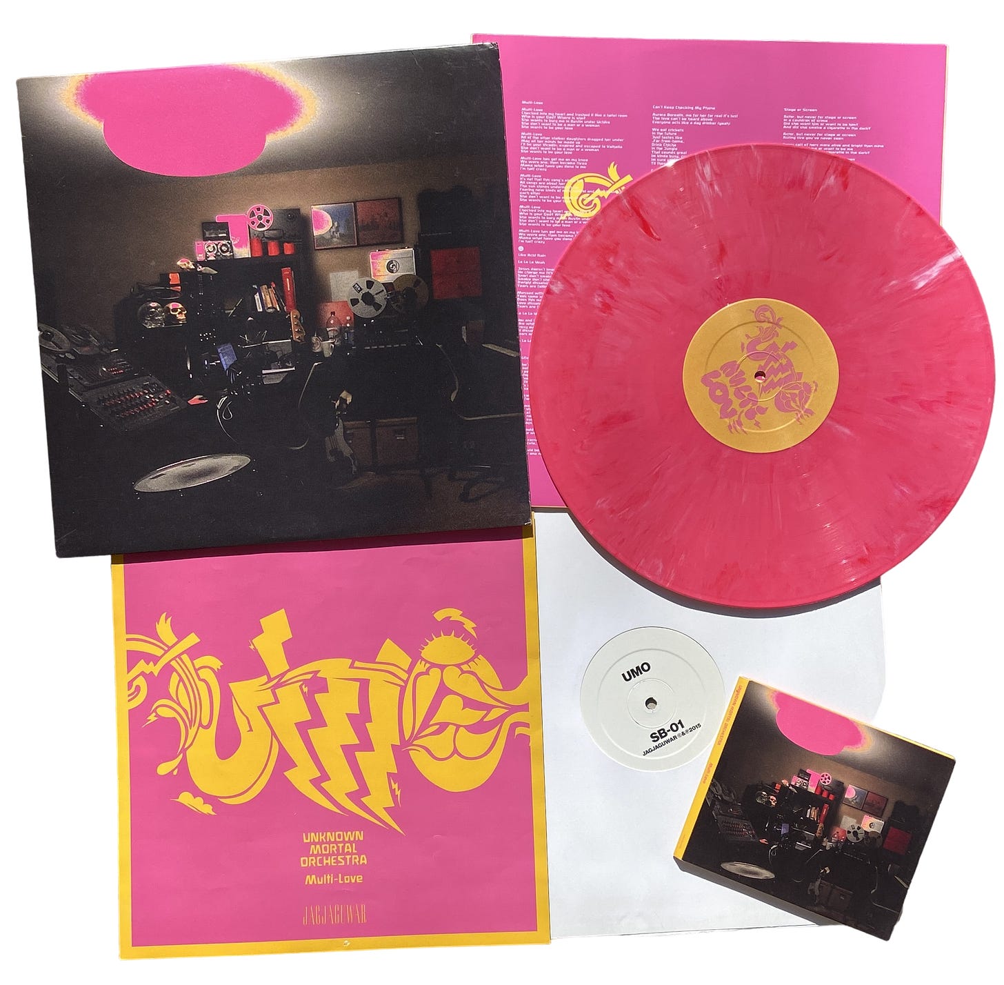 clockwise from top left: the record cover for UMO’s Multi-Love, the record sleeve, the limited-edition pink splatter vinyl, SB-01/SB-02 on vinyl, the Multi-Love cd, and a pink & yellow poster that were all included in the deluxe album bundle.