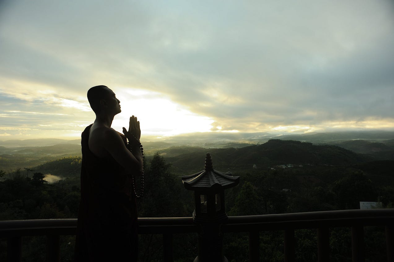 monk greeting the sunrise with “namaste”