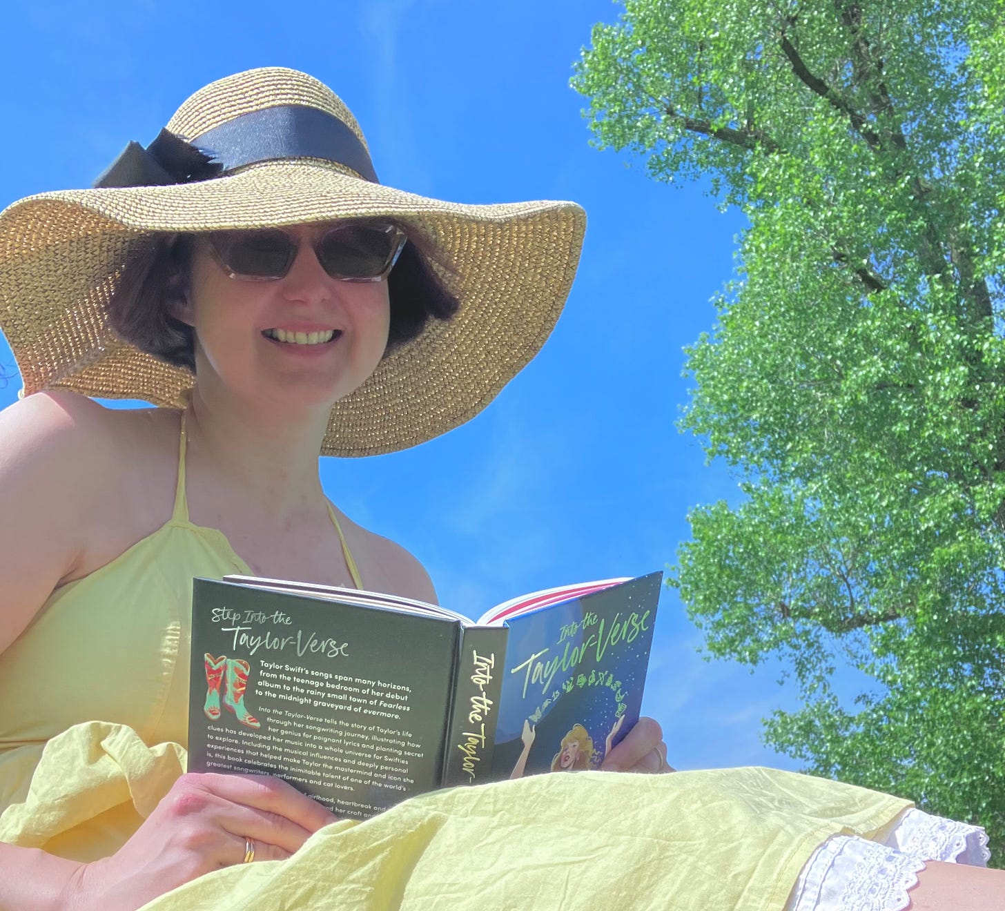 A smiling woman sitting in the park, holding a book