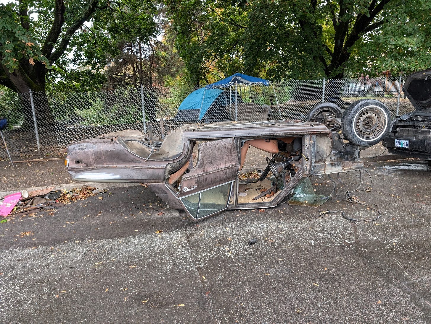 Husk of a car, stripped of parts, upside down and undriveable