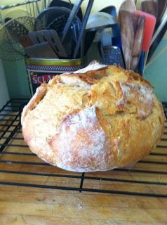 Round loaf of sourdough bread cooling on a rack