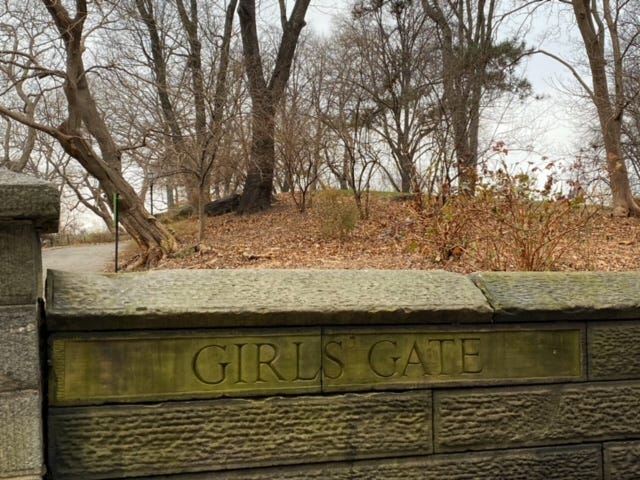 A low stone wall at an entry path to Central Park. It is engraved, "Girls Gate."