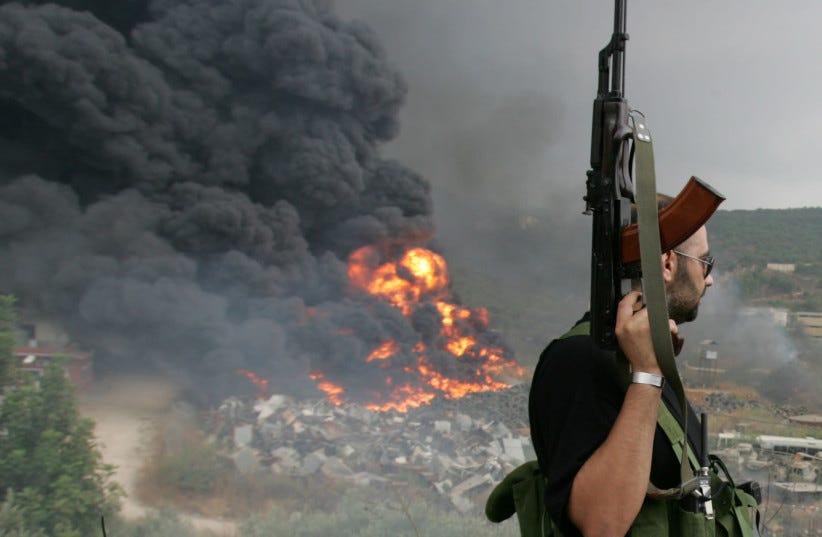 A Lebanese Hezbollah guerrilla looks at a fire rising from a burning object in a Beirut suburb, Lebanon July 17, 2006. (photo credit: REUTERS/ISSAM KOBEISI/FILE PHOTO)