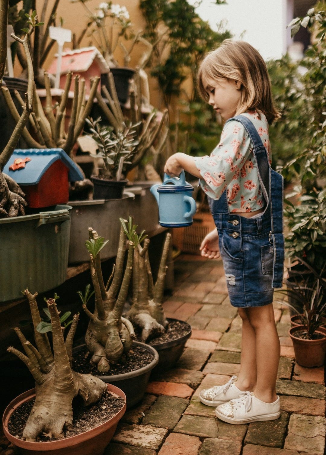 girl wearing blue romper holding teal watering can girl wearing blue romper holding teal watering can