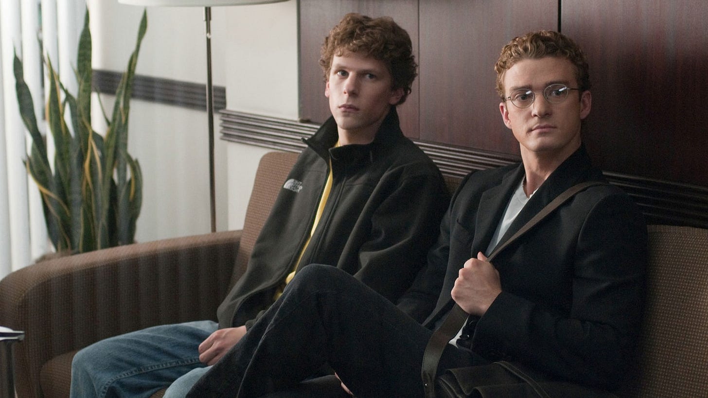 Jesse Eisenberg and Justin Timberlake sit on a couch in "The Social Network" (2010)