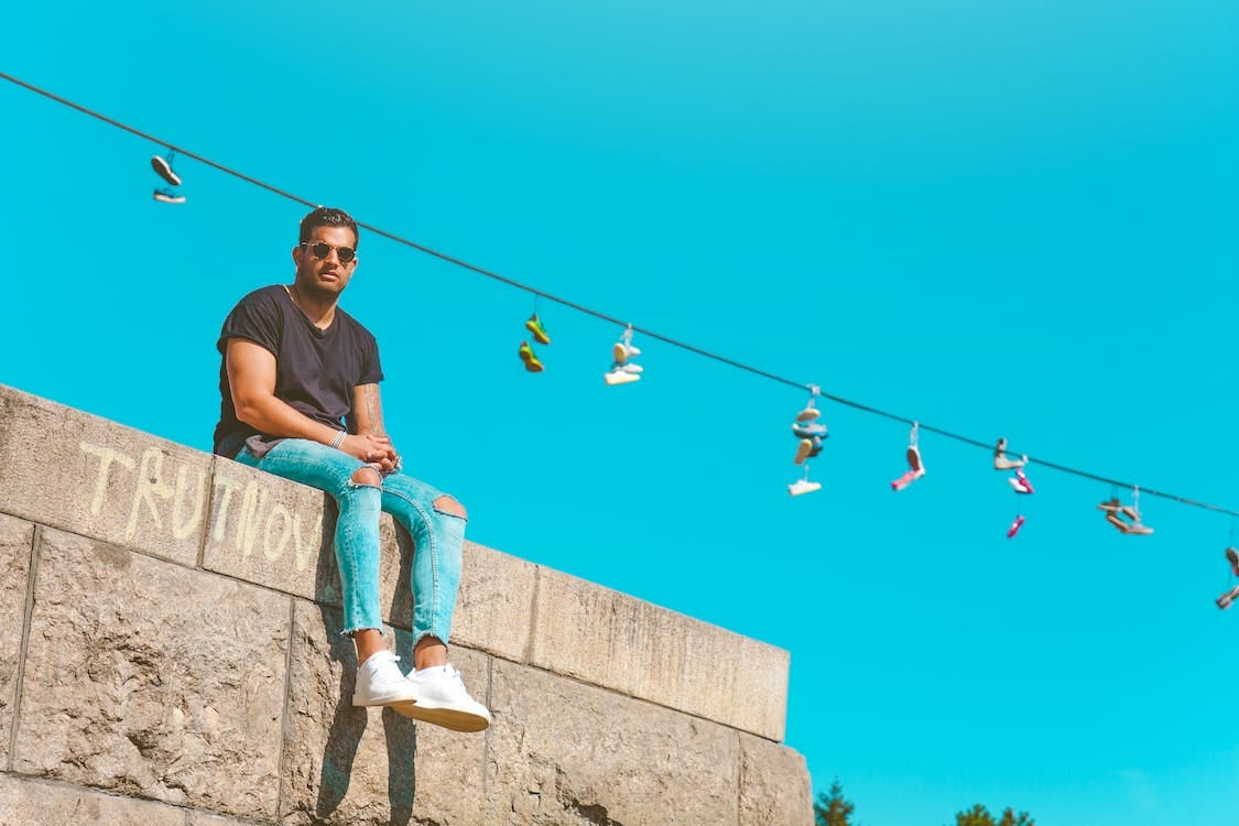 Free Low-angle Photography of Man Sitting on Pavement Under Blue Sky Stock Photo