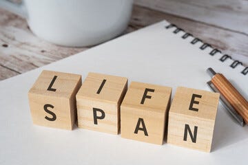 寿命のイメージ｜「LIFESPAN」と書かれた積み木とノートとペンとコップ