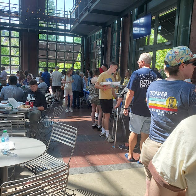 People lined up getting food from tables arranged in a horseshoe.