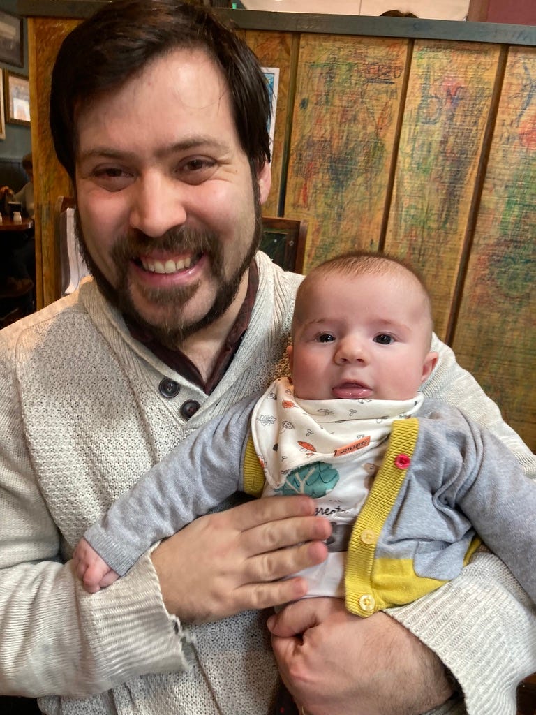 Me, a proud dad with a beard in my late 30s, holding my adorable 4-month-old son as he grins to the camera.