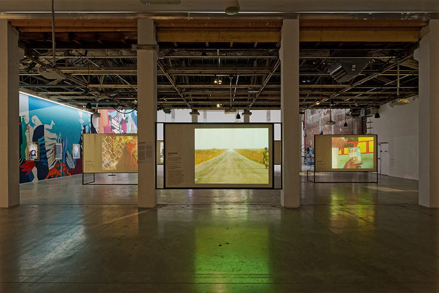 Screens projecting film in a cavernous warehouse type space