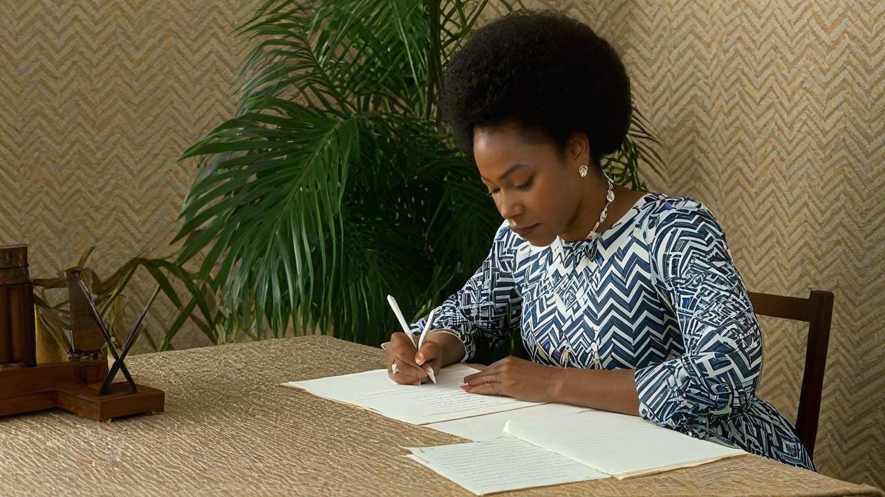 Black Woman sitting at a table writing a letter and praying