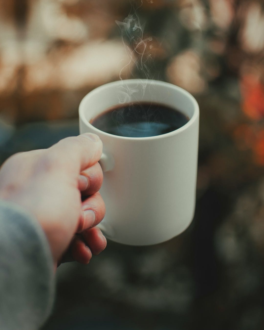 person holding white ceramic mug with brown liquid person holding white ceramic mug with brown liquid
