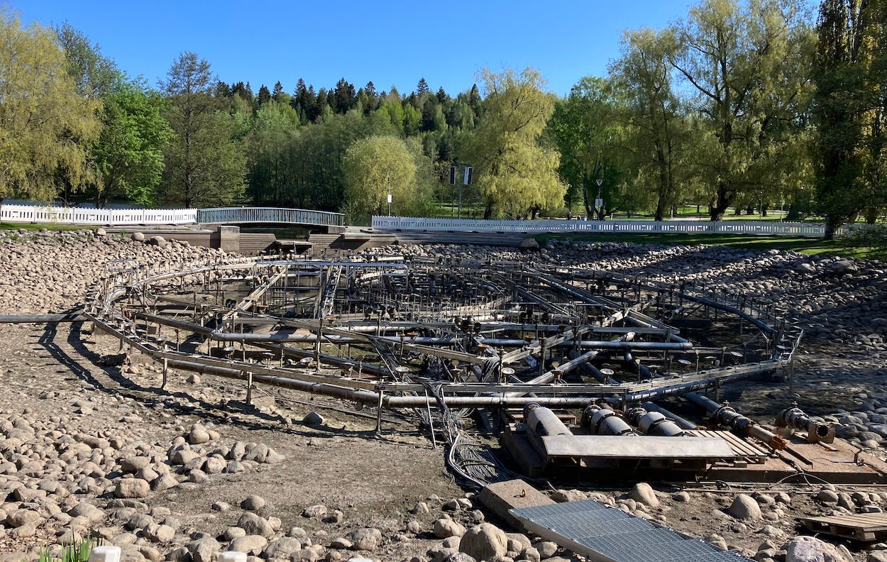 Drained ornamental lake exposing masses of piping for a fountain