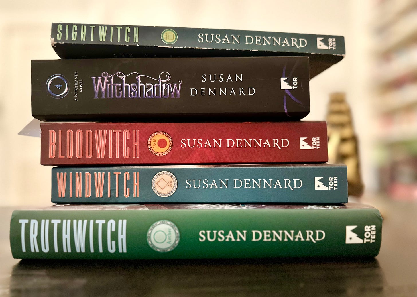 All of the Witchlands books stacked on Sooz's desk: hardcover of Truthwitch, paperbacks of Windwitch and Bloodwitch, UK paperback of Witchshadow, and paperback of Sightwitch