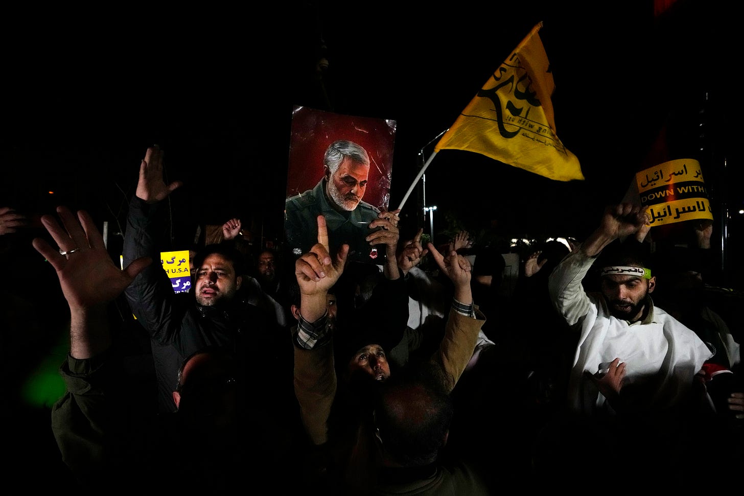 Iranian demonstrators chant slogans as one of them holds up a poster of the late Revolutionary Guard Gen. Qassem Soleimani, who was killed in a U.S. drone attack in 2020 in Iraq, during a protest against the U.S. and British military strike against Iranian-backed Houthis in Yemen, in front of the British Embassy in Tehran, Iran.