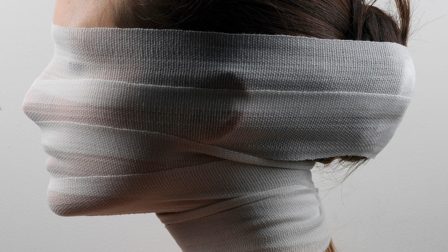 Side profile of model with their face wrapped up in white bandages