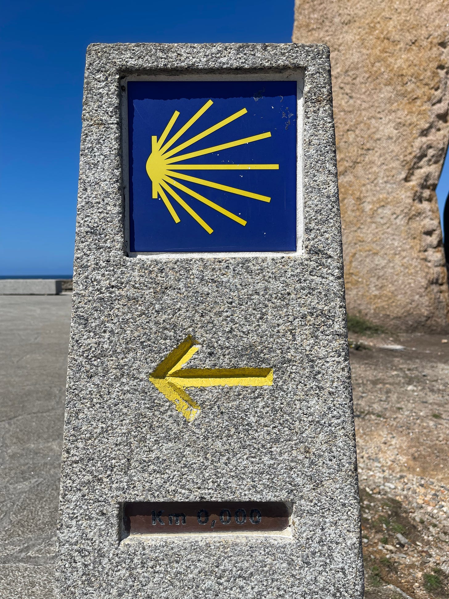 A marker along the road with Kilometer mark: 0,000 and the logo of the Camino