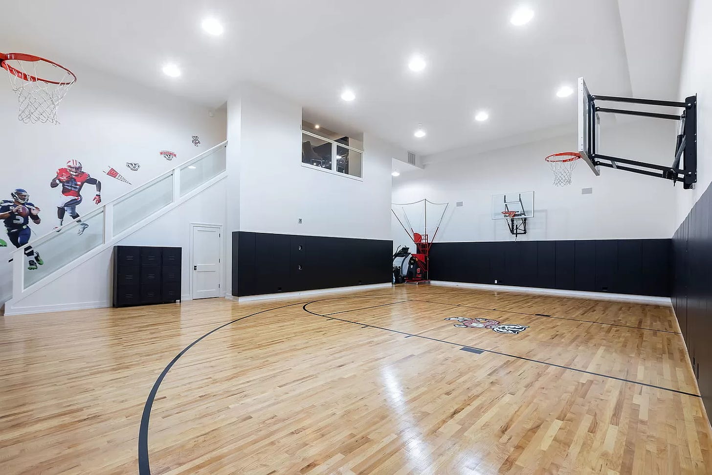 Another angle of the basketball court. There are some stickers of football players adorning a staircase that leads down onto the floor.