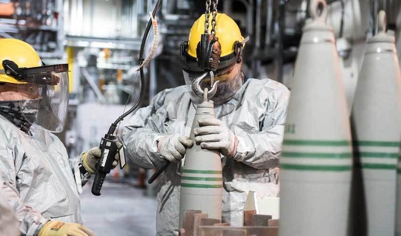 Operators wearing protective gear move objects in a warehouse-like area.
