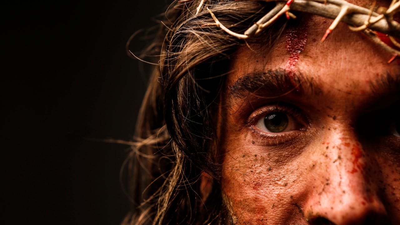 Jesus with a crown of thorns and blood on His face.