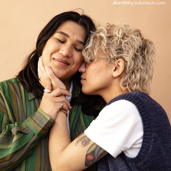 Two queer people embrace with peaceful faces.