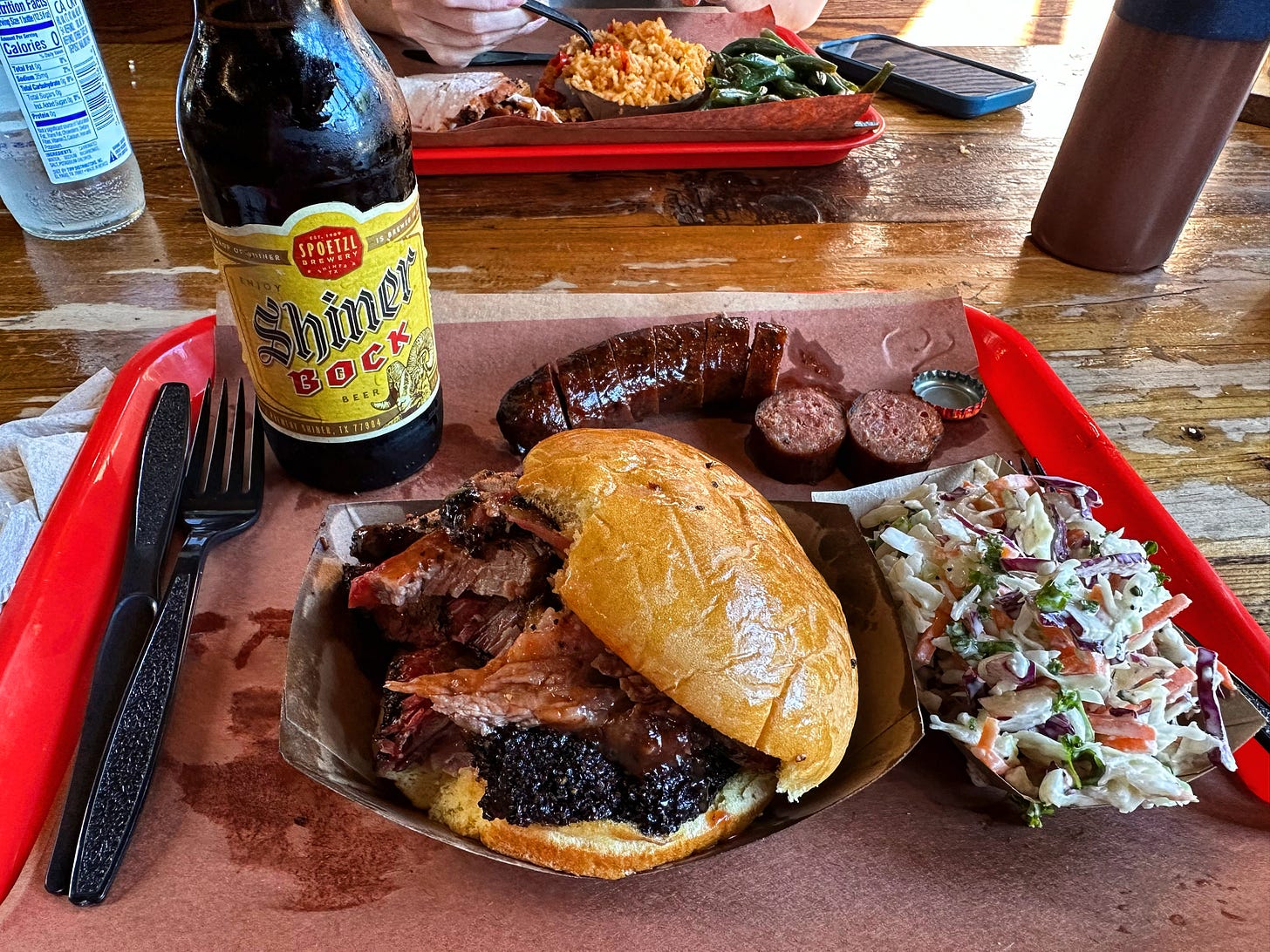 Tray of Texas BBQ with a brisket sandwich, sausage, cole slaw and a Shiner Bock beer