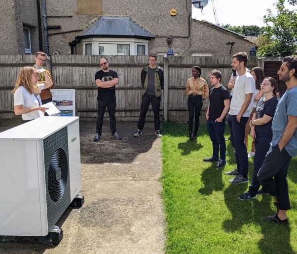 A group of people looking at a heat pump in a garden