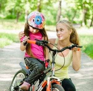 a mom talking to her daughter on her bicycle.