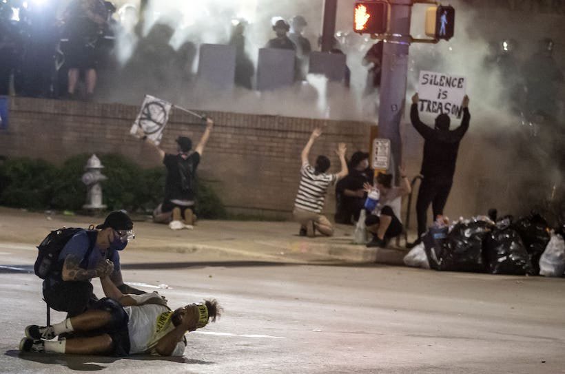 A man lies on the ground after being shot by police with less-lethal weapons during a protest in front of Austin Police Department headquarters