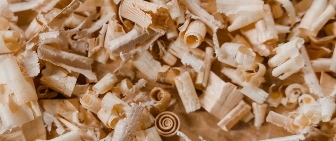 Free Detailed photo of wood shavings on a wooden surface. Ideal for carpentry and crafting themes. Stock Photo