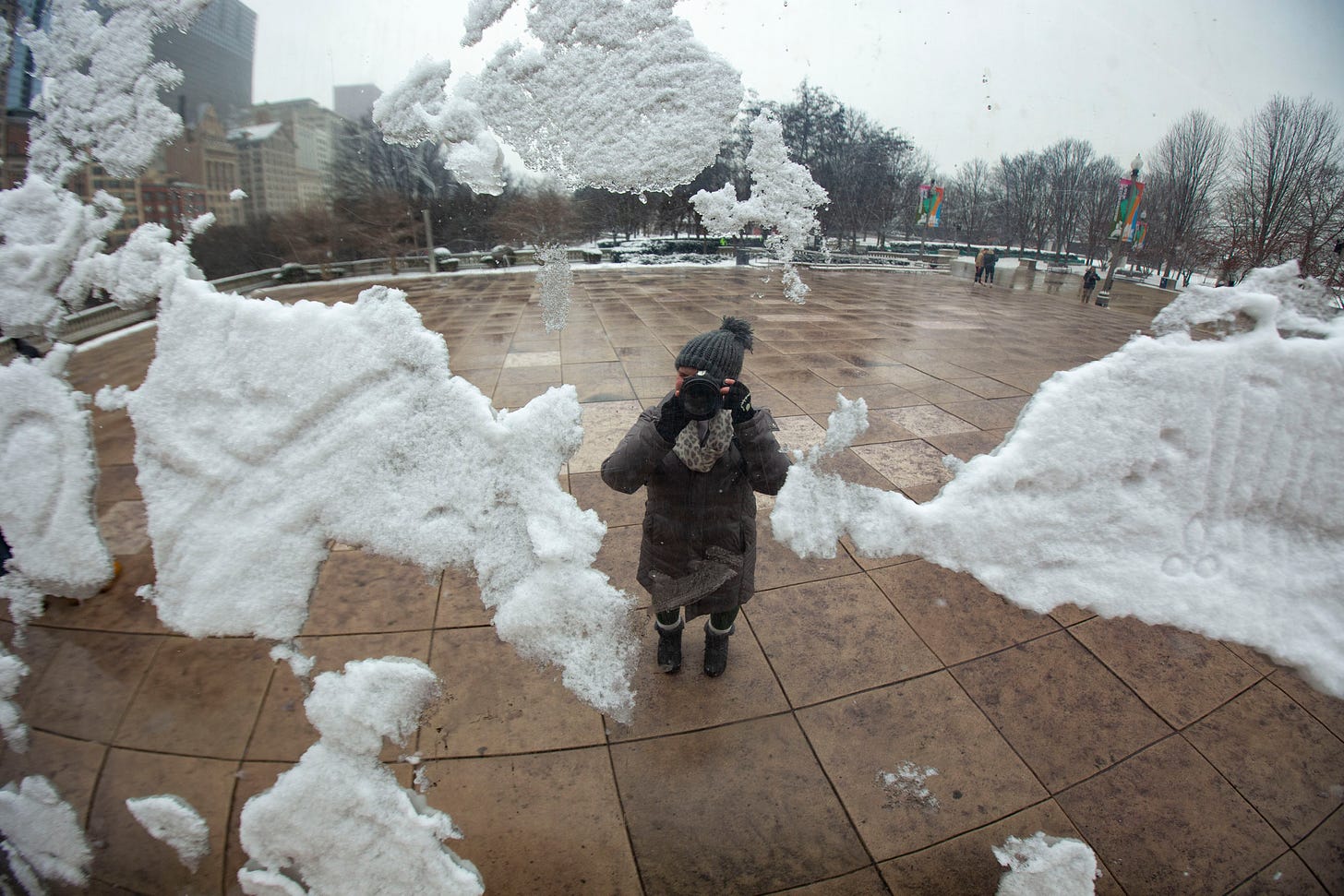 A woman taking a selfie in the Bean, which is covered with snow.