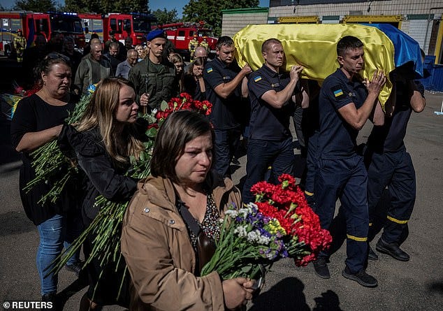 Rescuers and people attend a funeral ceremony of rescuer Ruslan Koshovyi who was killed by Russian troops in the city of Hostomel
