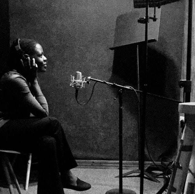 A black and white photo of a Kenyan woman in front of a microphone