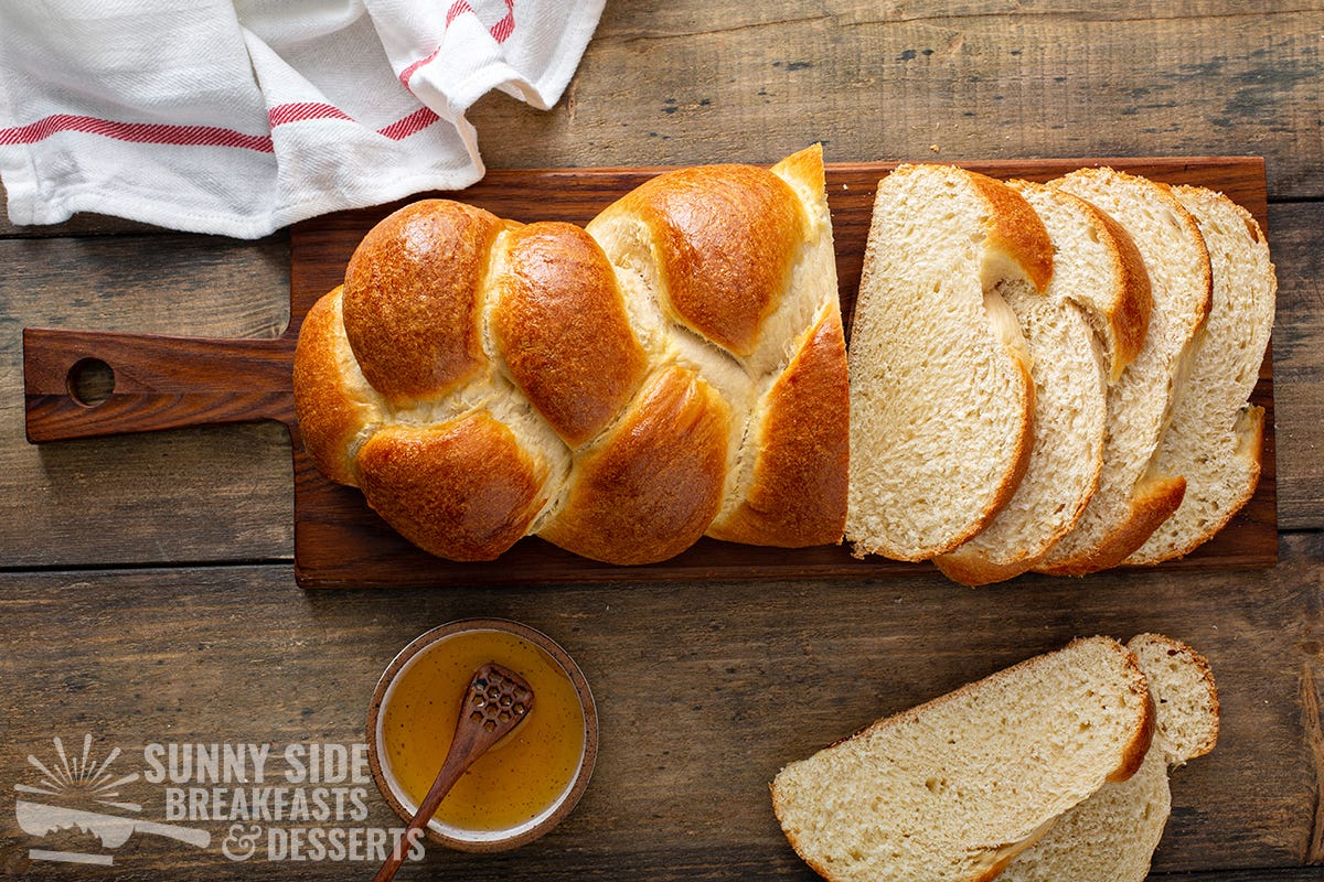 A golden loaf of challah partially sliced.