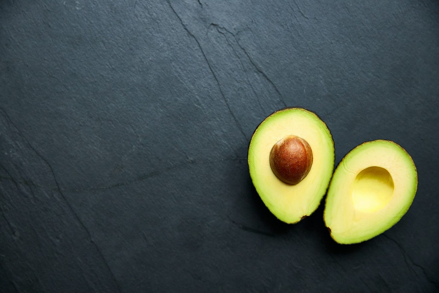 A split avocado, one half containing the pit, the other a cavity where the pit would be.