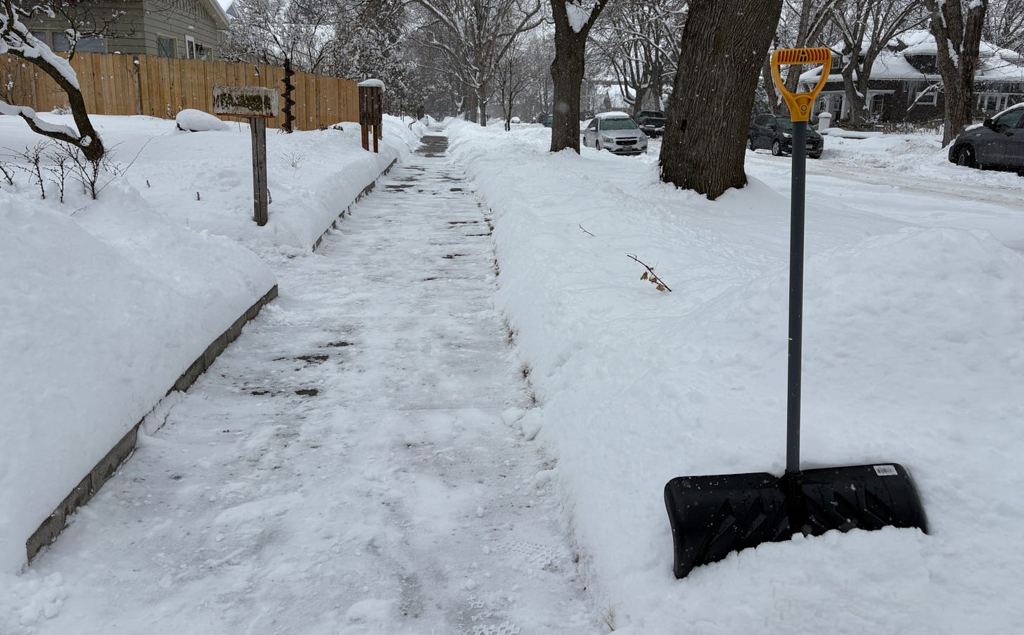 photo of snow shovel next to cleared sidewalk