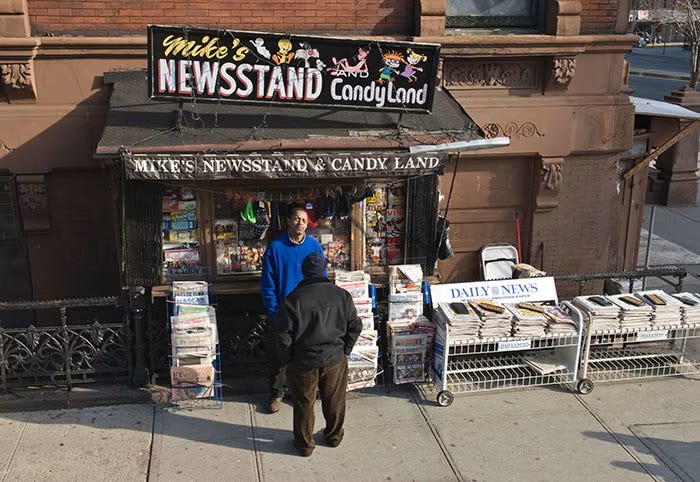 Image of a classic New York newsstand in the 1960s, with newspapers on a low wire rack