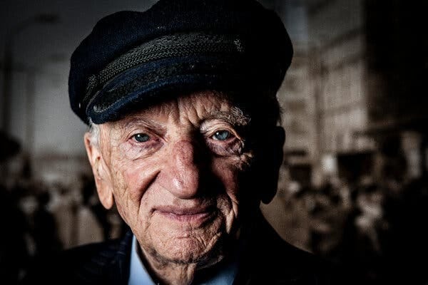 A color portrait of Benjamin Ferencz as a much older man, with a cap on his head and an inscrutable expression on his face.
