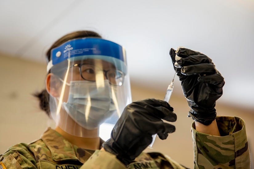 A soldier wearing a mask holds the COVID-19 vaccine.