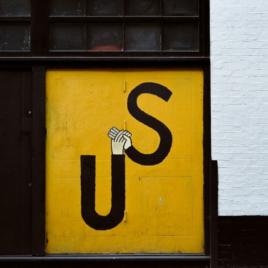 Door in brick wall painted yellow with a U and S both with hands embracing each others hands