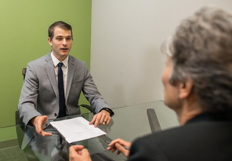 A man being interviewed for a job by the same interviewer as in the previous image.